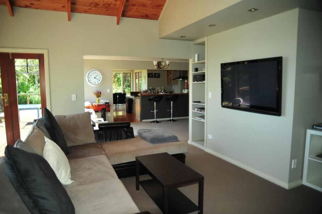 Shared lounge with sofa, open kitchen and timber ceiling at Georges BnB